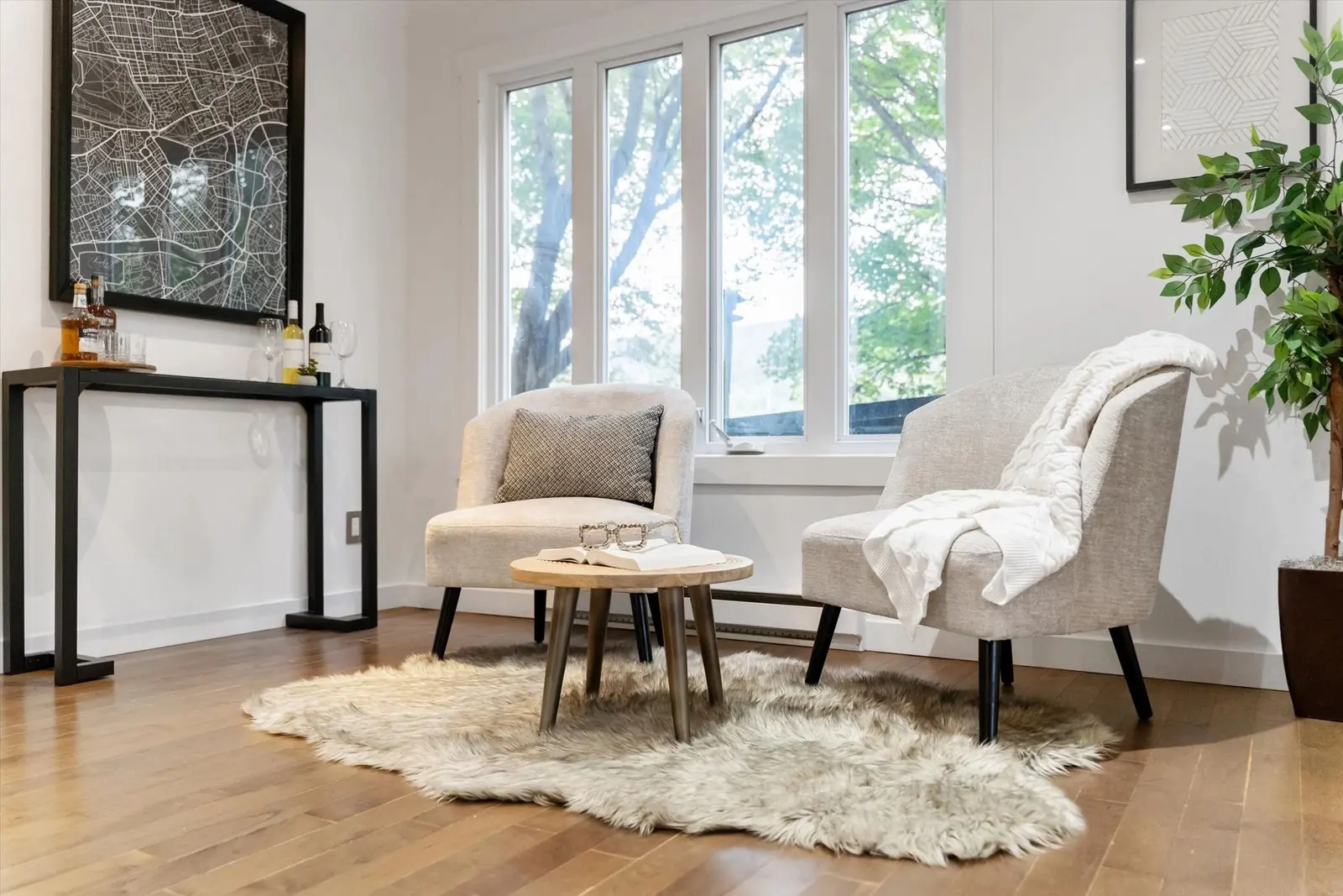 A staged sitting area with two armchairs and a small round table beside tall windows