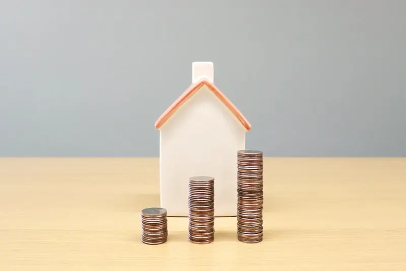 Model house beside three stacks of coins