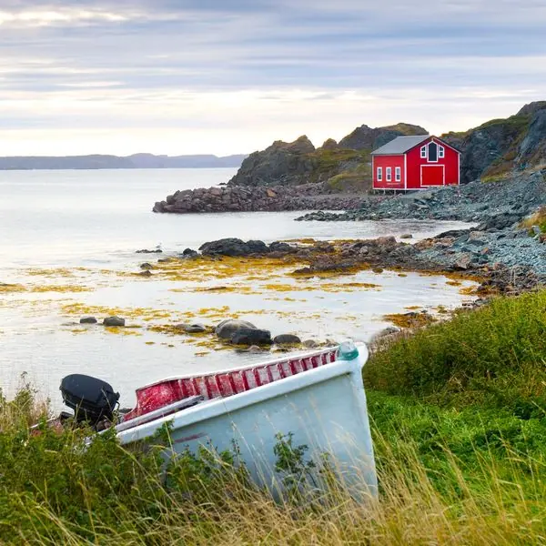 Cabane de pêche rouge et petit bateau sur une côte rocheuse