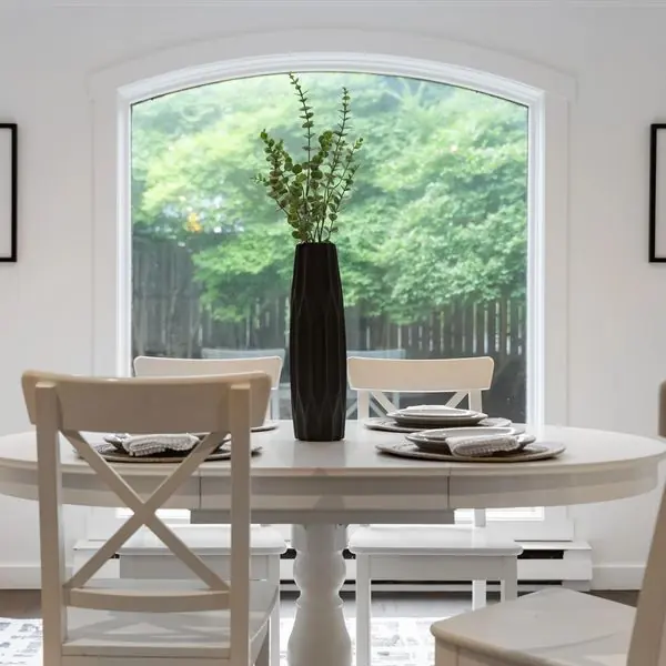 A quiet dining area with a round table set in front of a tall arched window